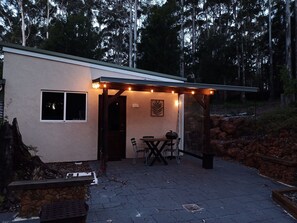 A covered patio area with a table and chairs, a small window, and a decorative leaf wall art piece. - Peaceful relaxing Getaway in Karri Forest bordering a Nature Reserve. (Kentdale)