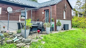 A wooden house with a sloped roof, a patio with outdoor furniture, and potted plants. - Vacation home Baur by Interhome (Neureichenau)