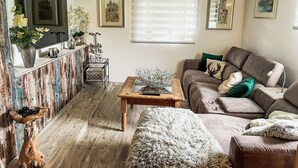 A cozy living room with a wooden floor, a brown sofa, a coffee table, and a TV mounted on a wooden cabinet. - Vacation home Baur by Interhome (Neureichenau)