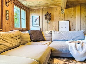 A cozy cabin interior with a wooden interior, a sofa, a framed picture, and a clock on the wall. - Winterberg by Interhome (Feldberg)