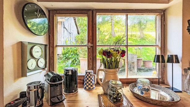 A kitchen with a wooden table, a coffee maker, a kettle, a pitcher, and a window with a view of greenery. - Winterberg by Interhome (Feldberg)