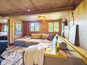 A cozy cabin interior with a sofa, a wooden table with a bottle and glasses, and a rug. - Winterberg by Interhome (Feldberg)