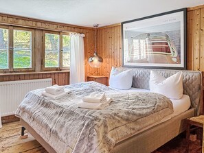 A bedroom with a large bed, a window with curtains, a hanging light fixture, and a framed picture on the wall. - Winterberg by Interhome (Feldberg)
