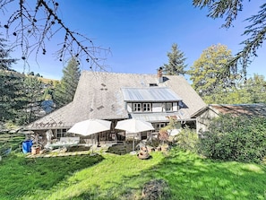 A house with a sloped roof, a front porch with umbrellas, and a garden area. - Winterberg by Interhome (Feldberg)