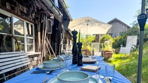 An outdoor dining table set with plates, glasses, and cutlery, surrounded by a rustic wooden building and greenery. - Winterberg by Interhome (Feldberg)