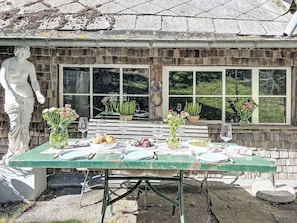 An outdoor dining area with a table set for four, surrounded by stone walls and windows. - Winterberg by Interhome (Feldberg)