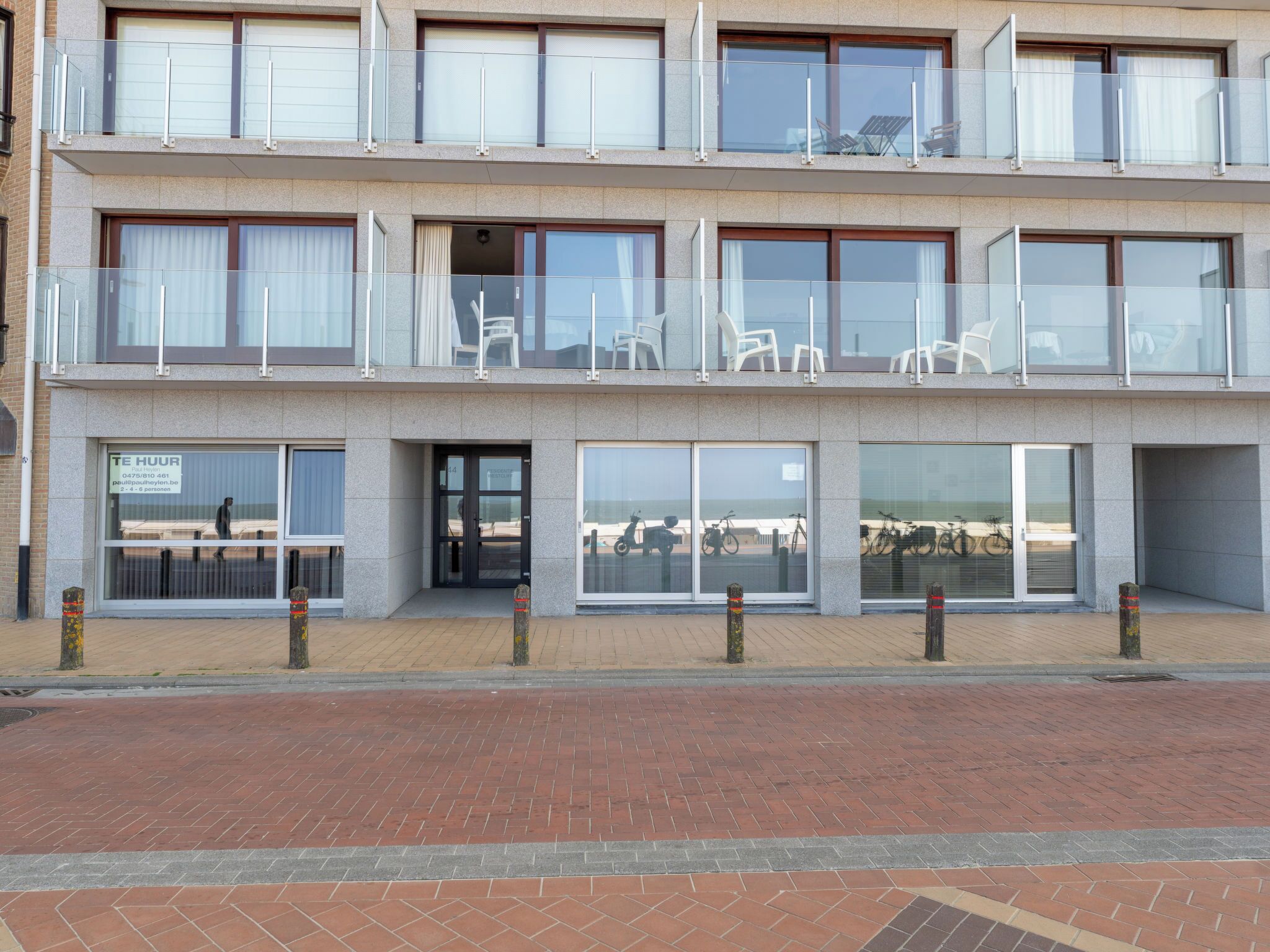 A multi-story hotel with a ground-level entrance, large windows, and outdoor seating areas.