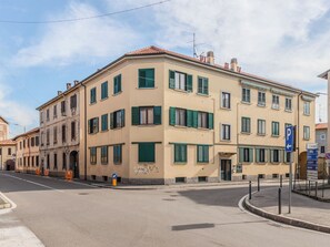 En byggnad med flera våningar, en beige fasad och gröna fönsterluckor, med en entré på bottenvåningen och en skylt som visar var man kan parkera.