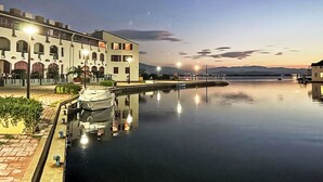 A waterfront hotel with a calm pool, a boat docked on the left, and a bridge in the background. - Coudalère/Les Hébrides by Interhome (Le Barcarès)