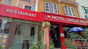 Un edificio a più piani con un ristorante e un albergo chiamati 'Unique Inn' al piano terra.