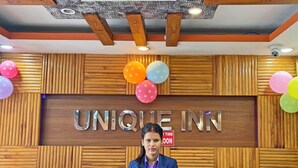 Una reception con pannello in legno e insegna che riporta 'UNIQUE INN'.