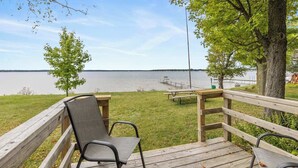 Una terraza de madera con un banco y una mesa de picnic que da a un lago tranquilo.