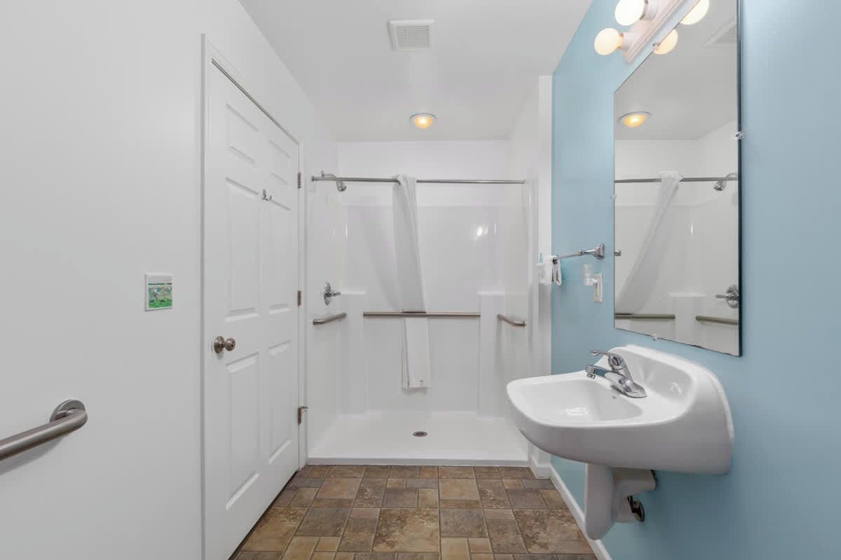 Un baño con lavamanos blanco, espejo y cabina de ducha.