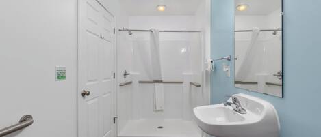 Un baño con lavamanos blanco, espejo y cabina de ducha.