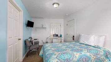 A bedroom with a bed, a desk, a chair, and a television.