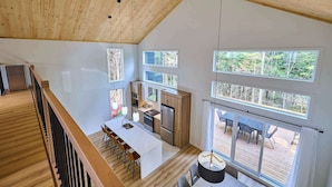 Una cocina moderna con ventanas amplias, un comedor con taburetes de bar y una terraza con mobiliario exterior.