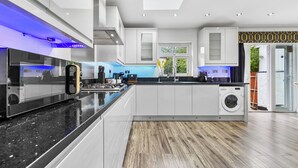 A modern kitchen with a central island, built-in appliances, and a washing machine. - 5 Bedrooms house near Wembley StadiumI Free parking I Discounts for Longer Stays (Wembley)