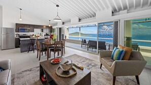 Eine moderne Küche mit Essbereich, ein großes Fenster mit Meerblick und eine gemütliche Sitzecke mit Blick aufs Meer.