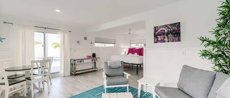 A modern living room with a sofa, armchair, and dining area.