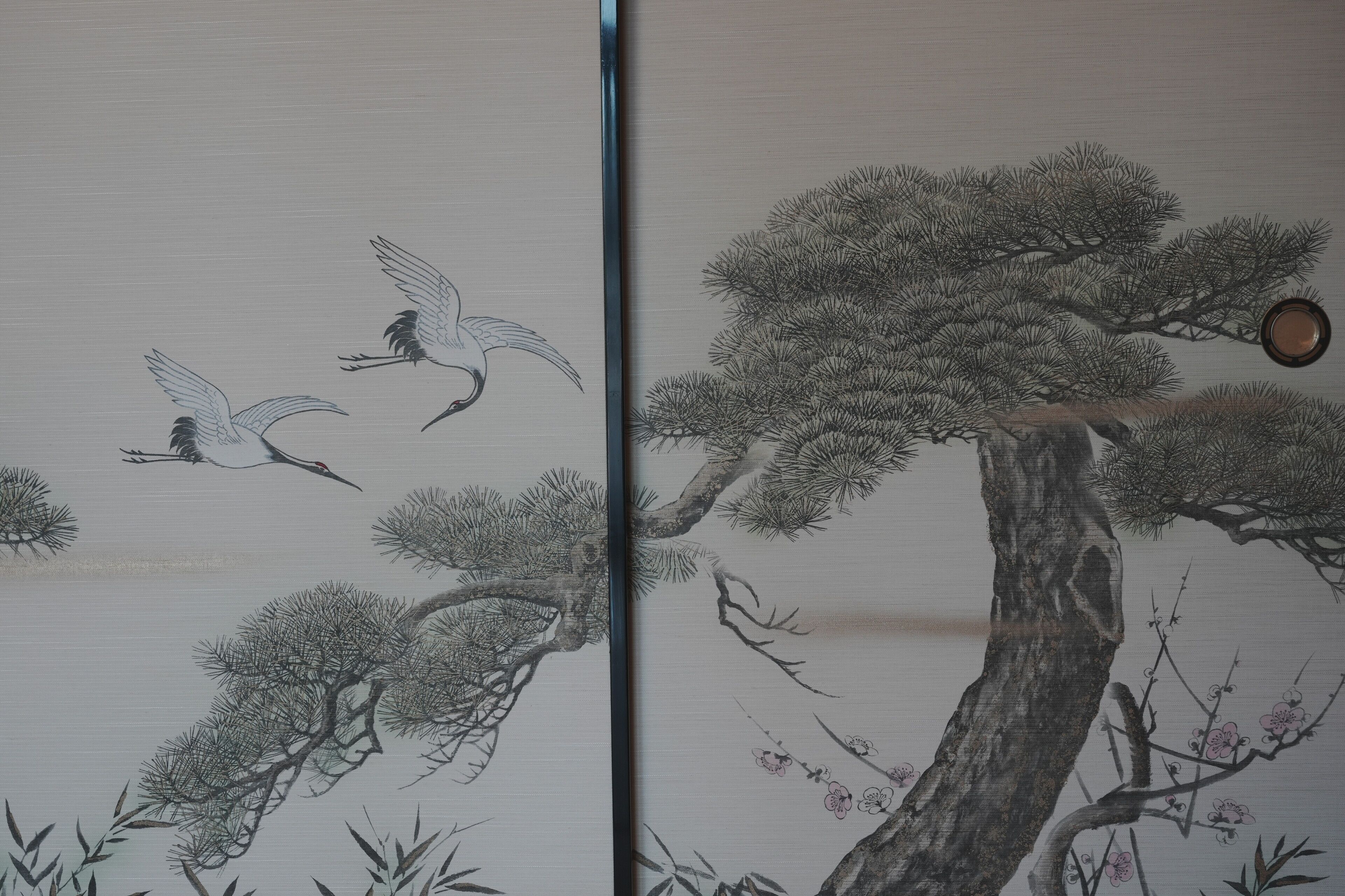 Una pintura china tradicional con grullas volando y un pino con flores.