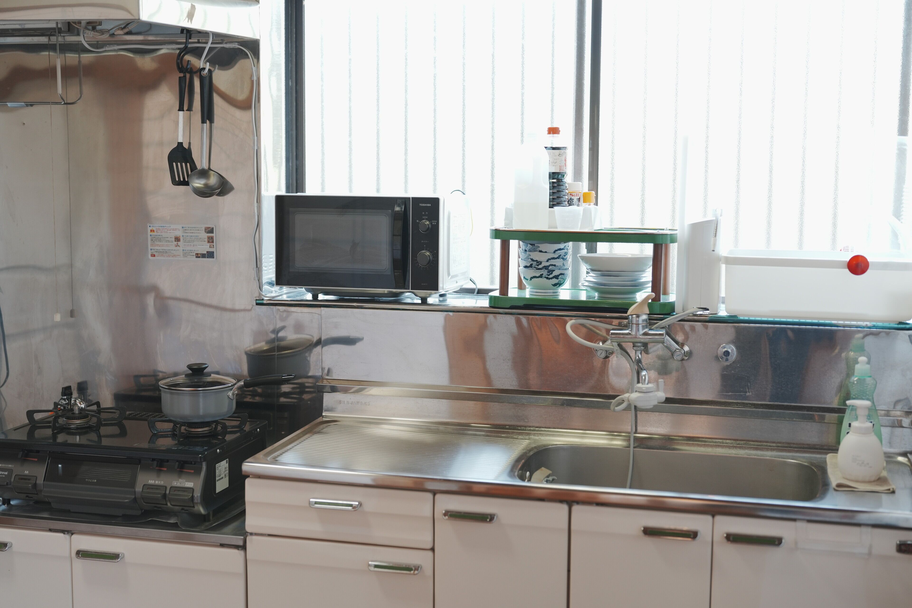 A kitchen with a stove, microwave, sink, and various utensils.
