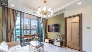 A modern living room with a sofa, a coffee table, a TV, and a balcony with curtains.