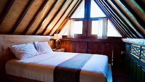 A bedroom with a wooden ceiling, a bed with white linens, a nightstand with a lamp, and a window with curtains. - Tegal Utu Villa (Ubud)
