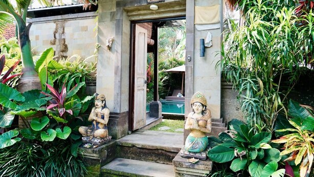A stone entrance with a sign reading "Villa A" leading to a pool area surrounded by lush tropical plants. - Tegal Utu Villa (Ubud)