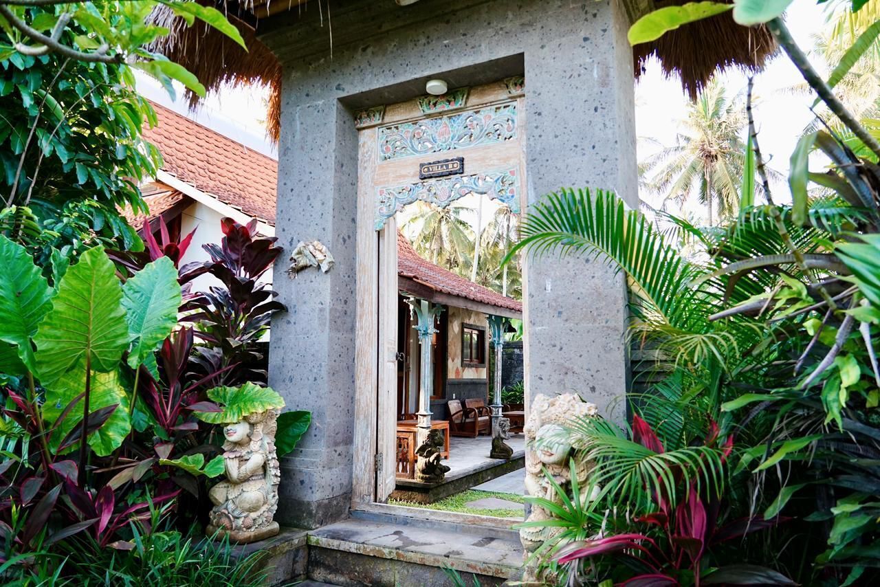 Une maison balinaise traditionnelle, avec un toit de chaume, une cour intérieure et une végétation tropicale luxuriante.