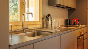 A modern kitchen with a stainless steel sink, a window with a view of greenery, and a red coffee machine. - Cosy apartment for 4 guests with WIFI, TV and terrace (Basse-nendaz)