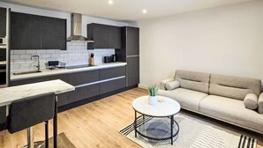 Una cocina moderna con armarios oscuros, una encimera blanca y una mesa de comedor redonda con sillas.