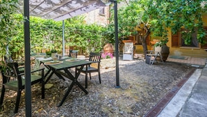 An outdoor patio with a pergola, tables, chairs, and potted plants. - Beautiful apartment for 7 people with WIFI and patio (Volterra)