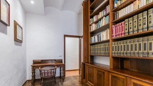 A study room with a wooden desk, a chair, and a large bookshelf filled with books. - Beautiful apartment for 7 people with WIFI and patio (Volterra)