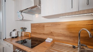 Una cocina moderna con encimera de madera, pileta de acero inoxidable y estufa integrada.