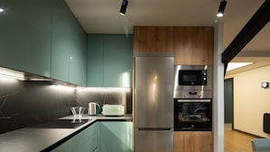 A modern kitchen with a stainless steel refrigerator, a built-in oven, and a microwave.