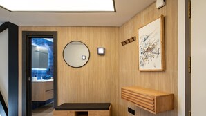 A modern bathroom with a wooden vanity, a round mirror, and a framed artwork on the wall.