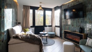A modern living room with a sofa, a round coffee table, a fireplace, and a TV mounted on the wall.