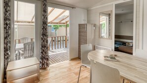 A modern kitchen with a wooden countertop, a dining area with a table and chairs, and an open balcony with a view of the outdoors. - Mobile home 35m² with terrace for 8 people, disabled access (Bormes-les-Mimosas)