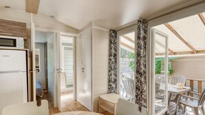A compact room with a kitchenette, a dining area, and a patio with outdoor furniture. - Mobile home 35m² with terrace for 8 people, disabled access (Bormes-les-Mimosas)