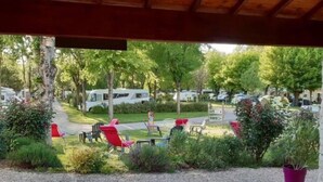 Vista de um camping com veículos recreativos estacionados ao longo de uma estrada, cercado por vegetação e áreas de estar ao ar livre.