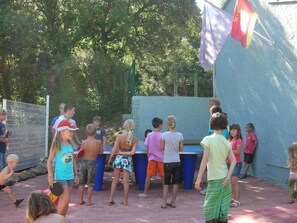 A group of children playing near a pool with a blue fence and trees in the background. - Mobile home with terrace in Bormes-les-Mimosas (Bormes-les-Mimosas)