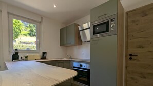 A modern kitchen with a large island, a microwave, and a built-in oven. - House for 4 in Gérardmer between lake and mountains with terrace (Gérardmer)