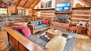 A cozy log cabin interior with a living room, kitchen, and dining area.