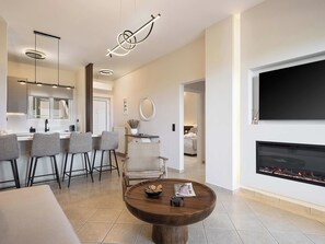 A modern living room with a fireplace, a dining area with bar stools, and a kitchen with pendant lighting. - Kymélia Upper Suite With Private Hot Tub & SeaView (Galatas)