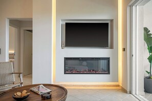 Una sala de estar moderna con chimenea, televisor de pantalla plana montado sobre ella y un área de estar cómoda con sofá y una mesita de centro.