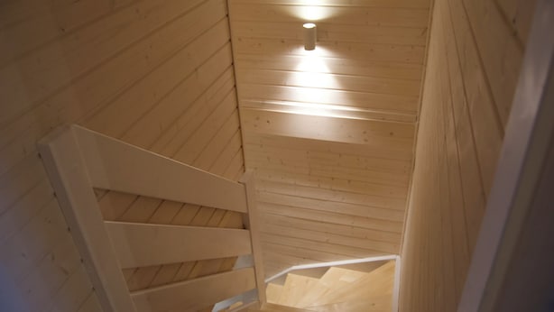 Una escalera de madera con una lámpara en la pared.
