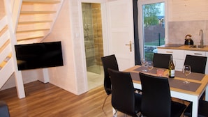 Una cocina moderna con comedor, una escalera y un televisor montado en la pared.