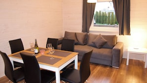 Una habitación con una mesa de comedor, sillas, un sofá y una ventana con cortinas.