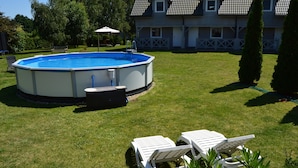 Una piscina con sillas de descanso y un jacuzzi en un patio trasero.