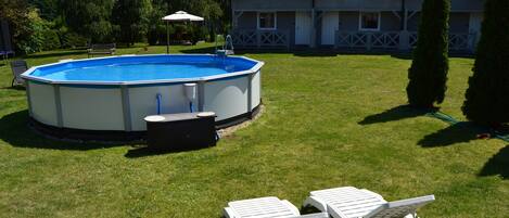A swimming pool with lounge chairs and a hot tub in a backyard.